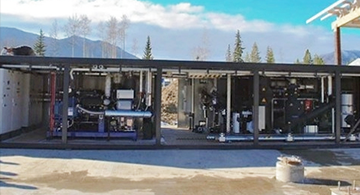 Vue extérieure d’une unité modulaire de production d’électricité géothermique installée dans un grand conteneur en acier ouvert.