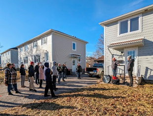 Un groupe de personnes à l'extérieur d'une maison pendant la démonstration du test d'étanchéité à l'air