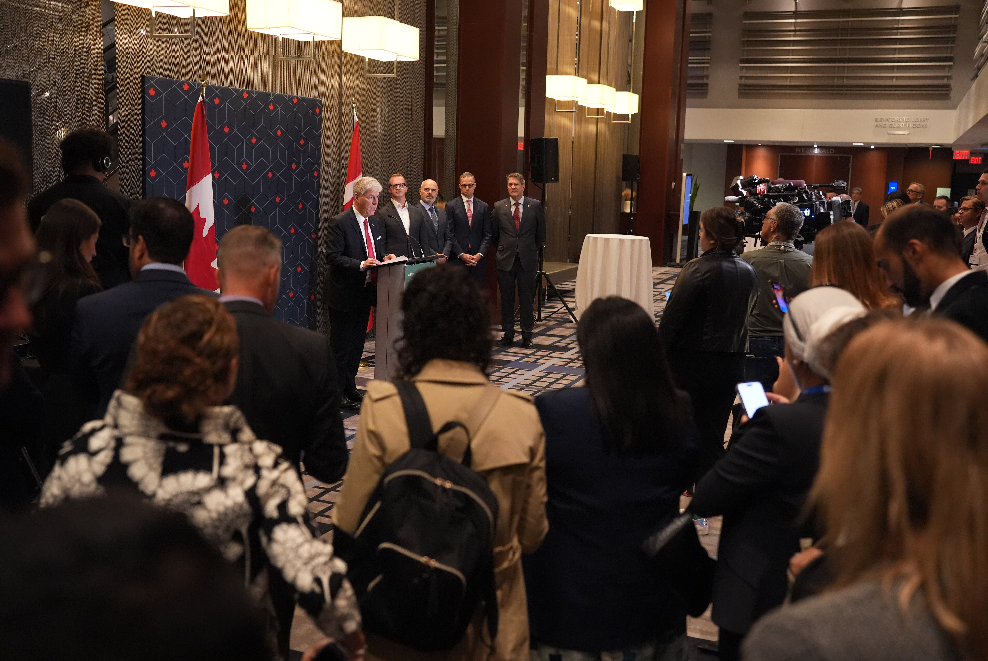 Minister of Energy and Natural Resources and 4 others from NorthX and Acra standing at the podium in front of a crowd. 