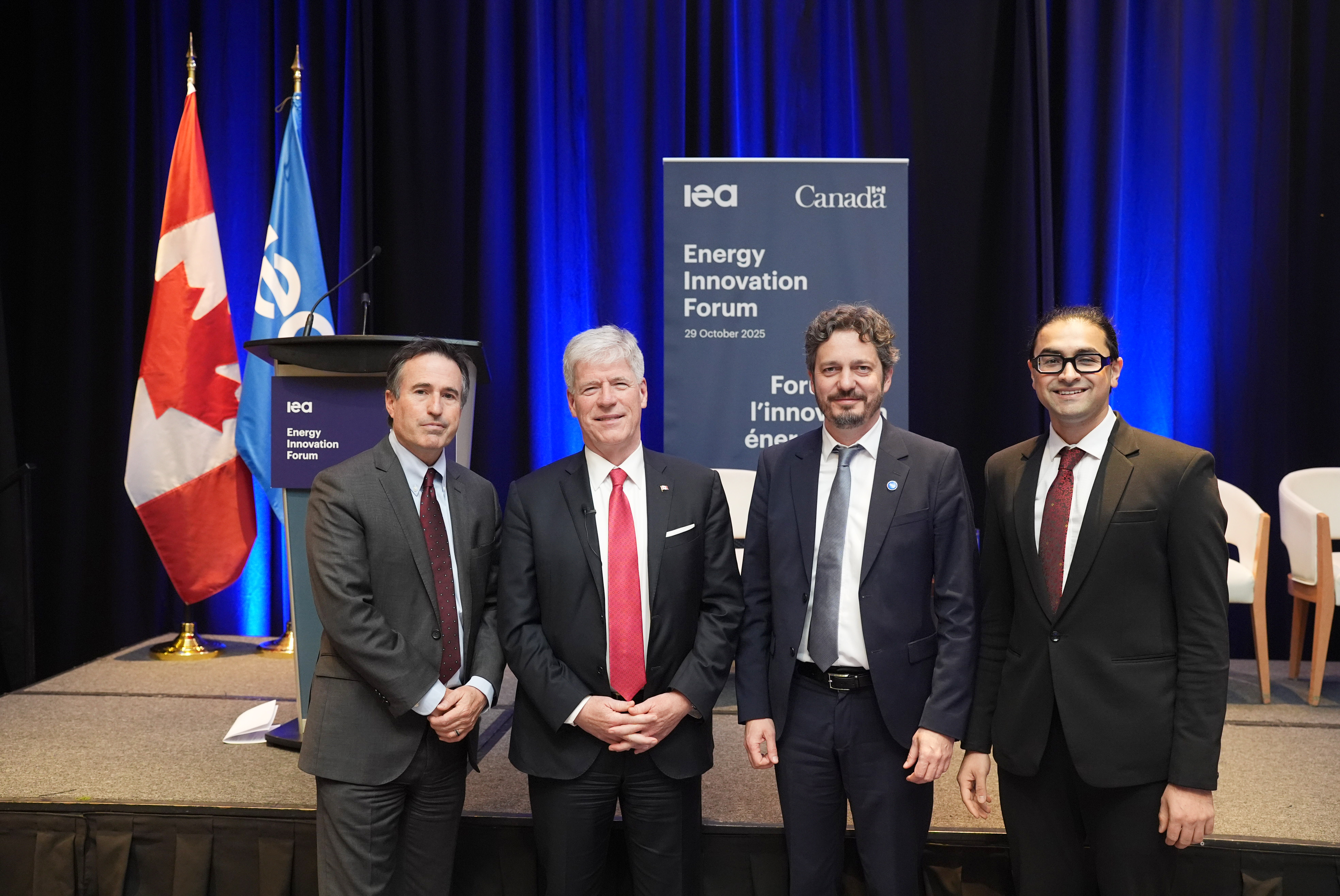 4 event attendees standing in front of the podium and Energy Innovation Forum banner 