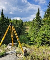 Trépied d'arpentage installé dans une zone boisée sur la frontière internationale dans la section des hautes terres, à l'est de Saint-Théophile (QC) et du Maine.