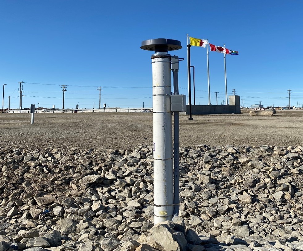 Station de recherche de l'Extrême-Arctique à Cambridge Bay, au Nunavut, avec des poteaux électriques et des drapeaux en arrière-plan.