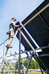 Un travailleur sur une échelle installe un panneau solaire par une journée ensoleillée.