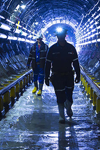 Deux travailleurs de Cameco portant un casque de sécurité traversent un tunnel souterrain.