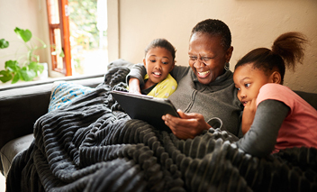 Une grand-mère et ses petites-filles regardant en continu sur une tablette.