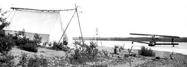 Avion sur l’eau et une tente sur le côté de la rivière.