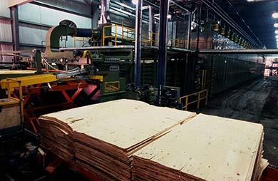 Trois piles de contreplaqués sur une plate-forme, dans une usine